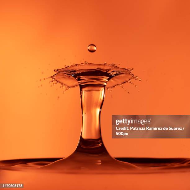 close-up of splashing droplet against orange background,mexico city,mexico - high speed photography stock pictures, royalty-free photos & images