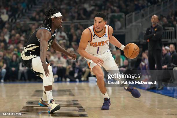 Devin Booker of the Phoenix Suns dribbles the ball against Jrue Holiday of the Milwaukee Bucks in the first half at Fiserv Forum on February 26, 2023...