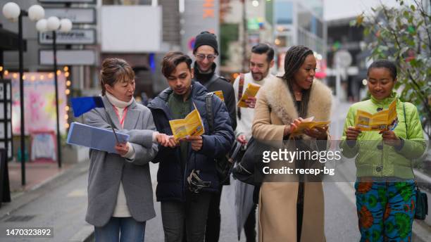 multi-racial group of tourist friends exploring city with local tour guide in tokyo - japanese culture on show at hyper japan stock pictures, royalty-free photos & images