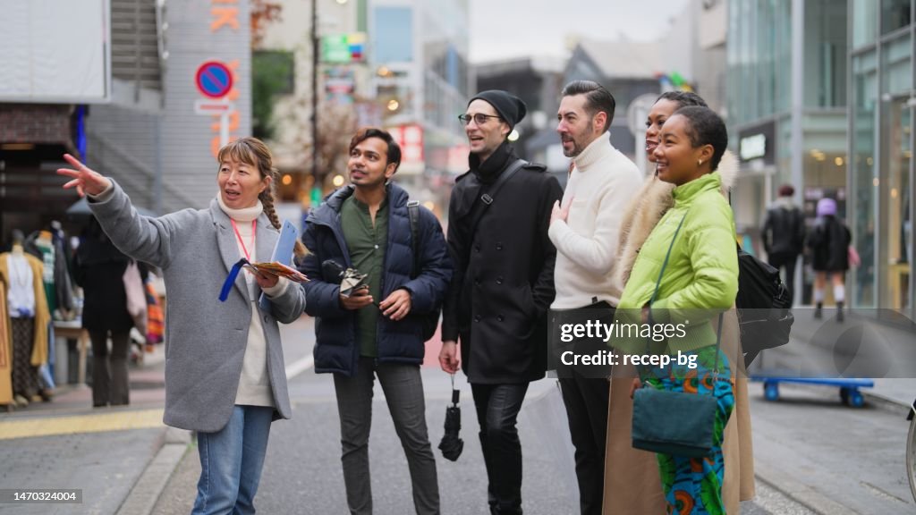 Multi-racial group of tourist friends exploring city with local tour guide in Tokyo