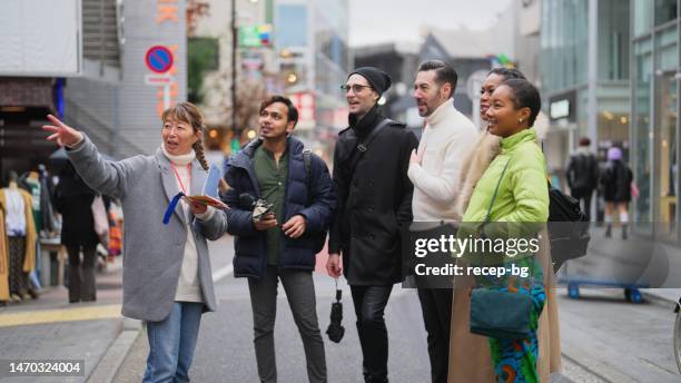 multi-racial group of tourist friends exploring city with local tour guide in tokyo - indian tour guide stock pictures, royalty-free photos & images