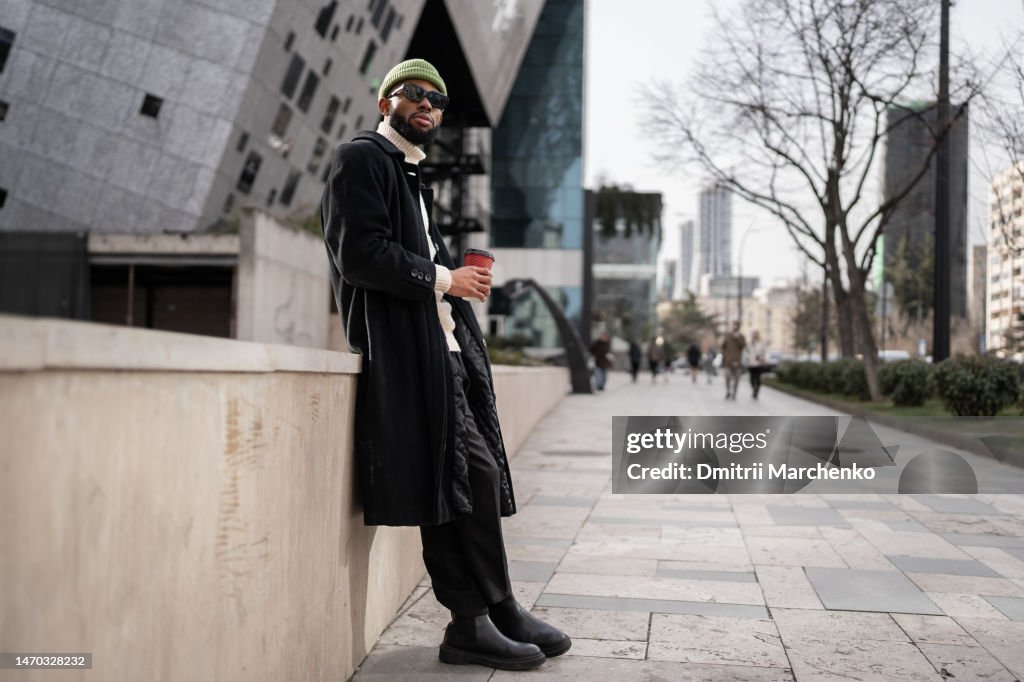 Carefree calm black man near modern building with cup of coffee good morning free from work and duty