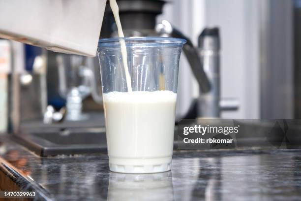 oat milk - pouring a drink into a transparent plastic cup - milk bottles stock pictures, royalty-free photos & images