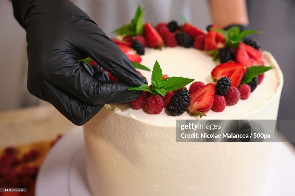 Pastry chef black gloves making strawberry homemade white cream cake