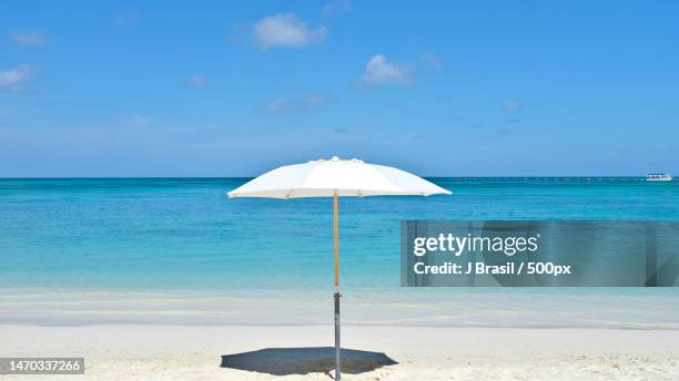 the most peaceful place on earth,palm beach,aruba - beach umbrella sand stock-fotos und bilder