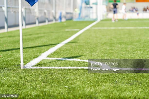 side view of a soccer field:s flagpole and goal. close up of a flag pole and a goal at the distance, - turf fotografías e imágenes de stock