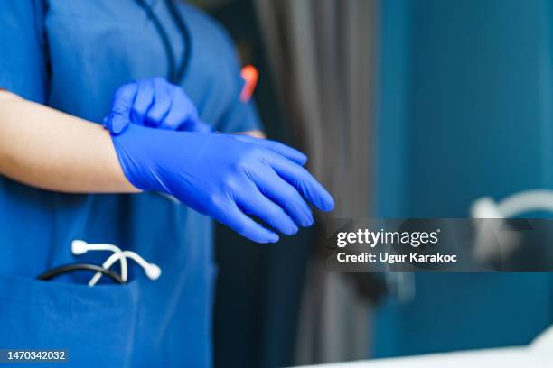 healthcare worker wearing blue protective gloves - nursing scrubs stock pictures, royalty-free photos & images