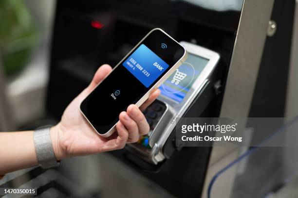 close up of female hand making mobile payment with smartphone in the shop - communication en champ proche photos et images de collection