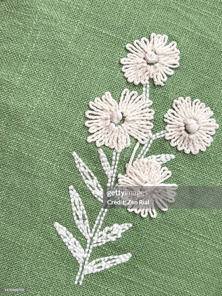 Botanical pattern embroidered on a green decorative pillow