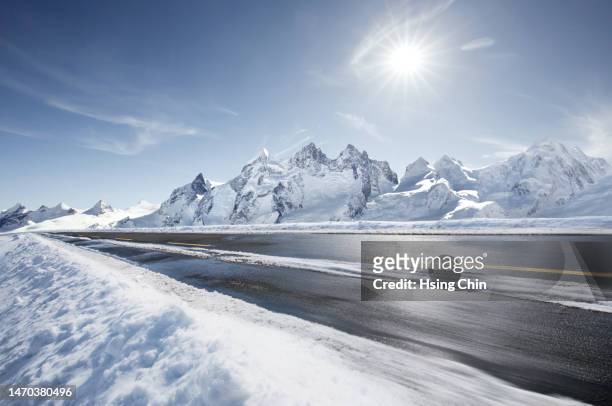 backlit snow mountain road - snow road stock-fotos und bilder
