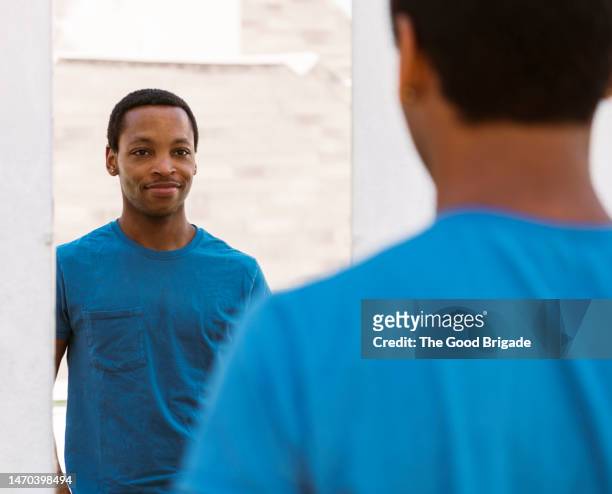 smiling man looking at reflection in mirror - rear view mirror - fotografias e filmes do acervo