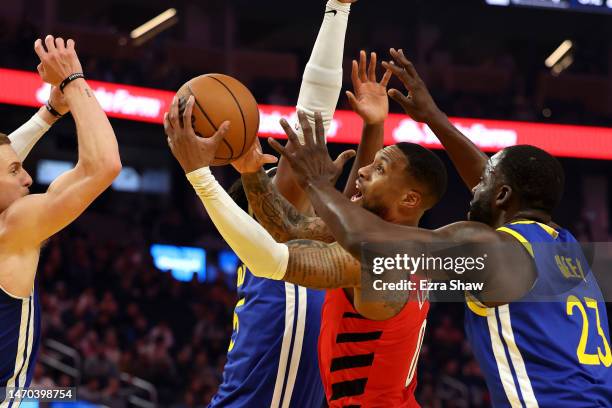 Damian Lillard of the Portland Trail Blazers goes up for a shot on Donte DiVincenzo and Draymond Green of the Golden State Warriors at Chase Center...