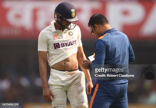 Shubman Gill of India receives medical treatment during day one of the Third Test match in the series between India and Australia at Holkare Cricket...