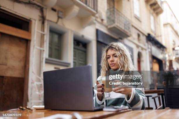 beautiful young woman working online from the outdoor cafe - malta business stock pictures, royalty-free photos & images