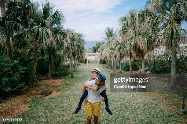 father giving piggyback ride to daughter - okinawa prefecture stock pictures, royalty-free photos & images