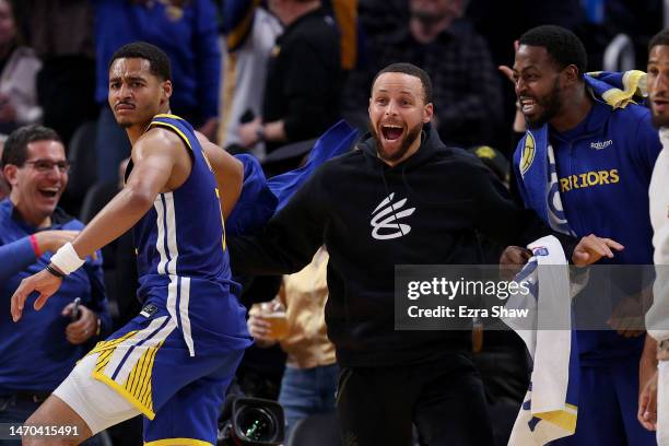 Injured Stephen Curry of the Golden State Warriors celebrates with teammates after Jonathan Kuminga of the Golden State Warriors dunked the ball...