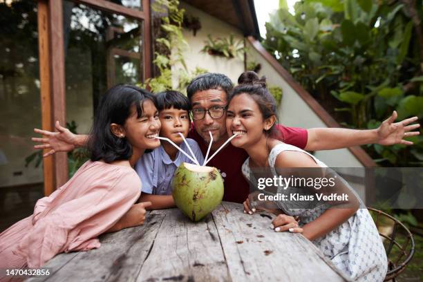 father enjoying coconut water with family - indonesischer archipel stock-fotos und bilder