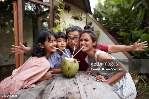 Father enjoying coconut water with family