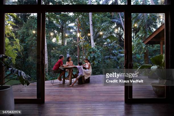 family enjoying vacation on resort porch - small child sitting on floor stockfoto's en -beelden