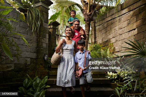 family moving down on steps at villa - asian family fall stock-fotos und bilder