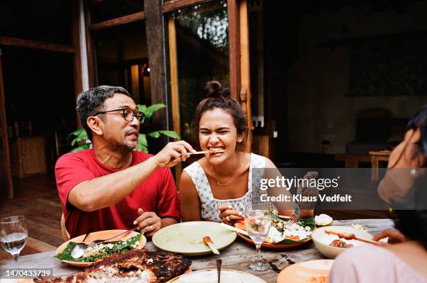 man feeding snack to woman at dining table - holiday dinner stock-fotos und bilder