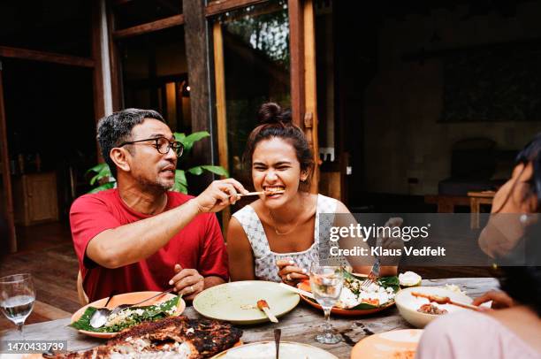 man feeding snack to woman at dining table - asian wife stock pictures, royalty-free photos & images