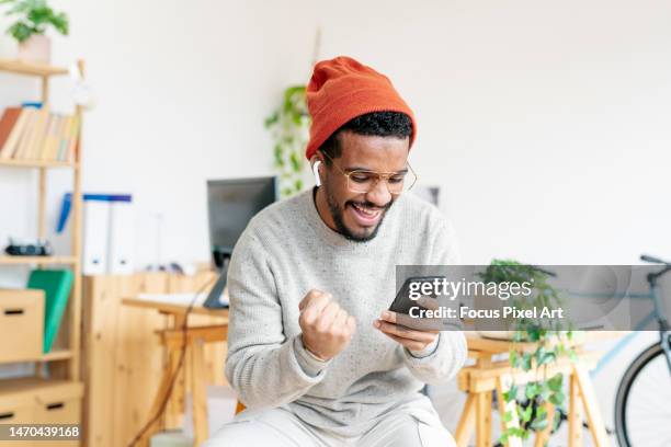 young entrepreneur looking at the mobile and celebrating. success and happiness concept. - boa notícia imagens e fotografias de stock