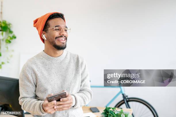 smiling young entrepreneur in his office having a conversation on the phone using a wireless headset. - bike headset stock-fotos und bilder