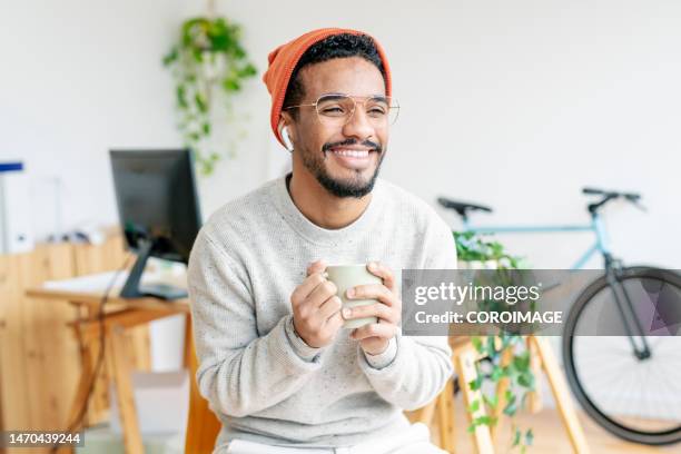 smiling young entrepreneur drinking coffee in the office. - coffee bike stock pictures, royalty-free photos & images