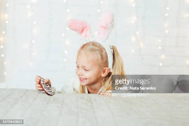 portrait of cute child little girl with bunny ears holding easter egg gingerbread - bunny eggs stock-fotos und bilder