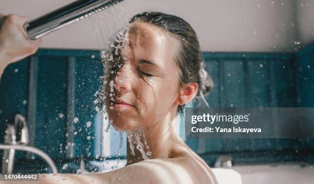 beautiful european young woman taking warm a shower in a sunlit bathroom - chuveiro instalação doméstica - fotografias e filmes do acervo