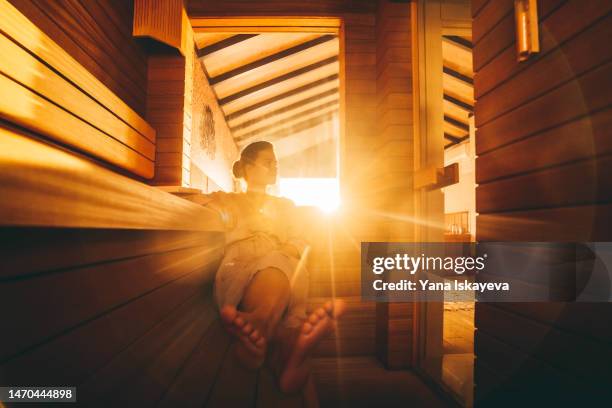 a young woman relaxing in an eco wooden sauna - hot sauna stock-fotos und bilder