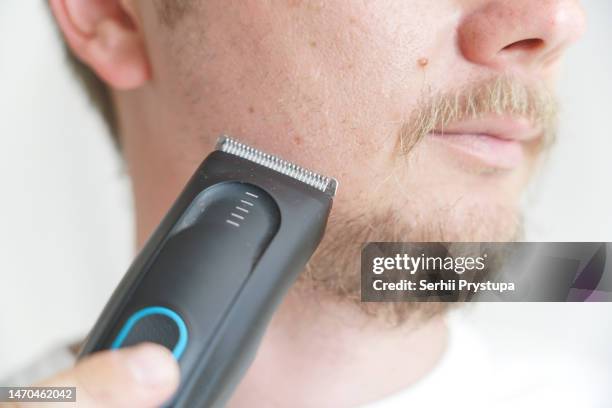 young man holding an electric razor - electric razor stock pictures, royalty-free photos & images