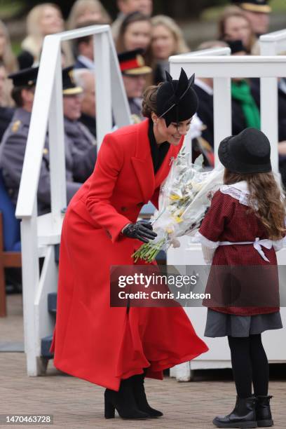 Catherine, Princess of Wales receives a bouquet of flowers from a child during a visit to the 1st Battalion Welsh Guards at Combermere Barracks for...