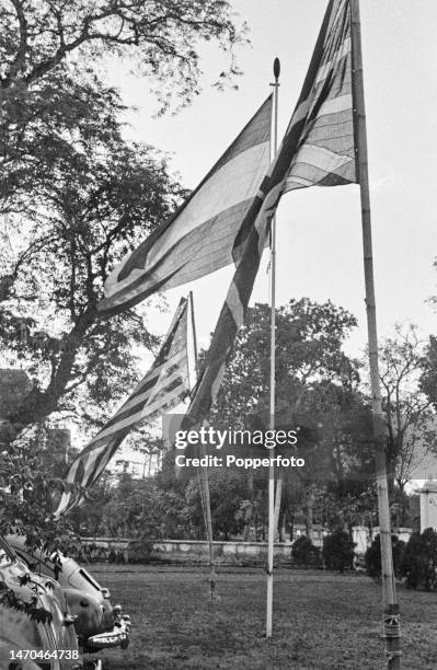 National flags of the United States, Dutch East Indies and Great Britain fly from flagpoles in the garden of the new Allied Headquarters compound on...