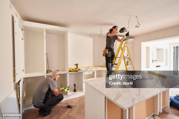 female electrician working in a kitchen remodelling - home improvement contractor stock pictures, royalty-free photos & images