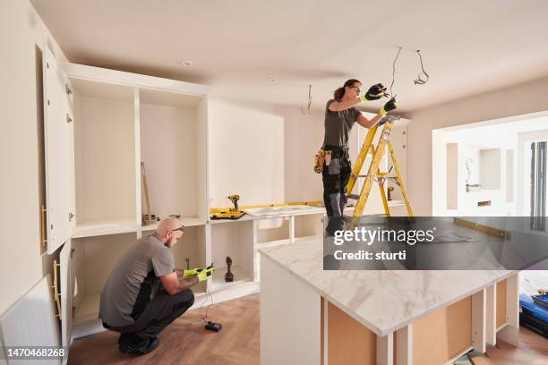female electrician working in a kitchen remodelling - ampliação da casa imagens e fotografias de stock