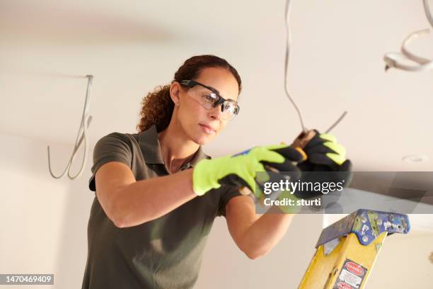 female electrician working in a kitchen remodelling - elektricien stockfoto's en -beelden