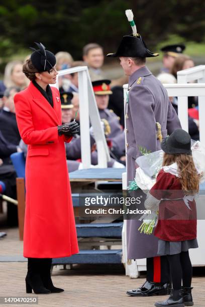 Catherine, Princess of Wales receives a bouquet of flowers from a child during a visit to the 1st Battalion Welsh Guards at Combermere Barracks for...