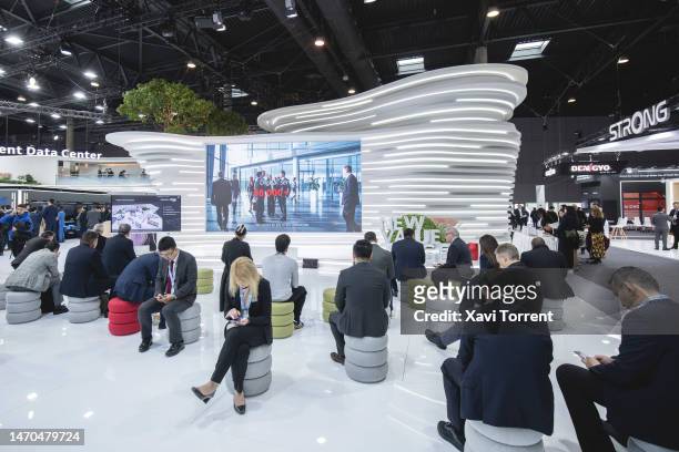 Visitors sit in front of a led screen at the Huawei Technologies Co. Booth on day 2 of the GSMA Mobile World Congress at Fira Barcelona on February...