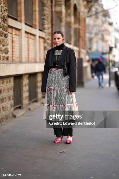 Guest wears red and silver earrings, a black wool turtleneck pullover, a red pearls necklace, a white lace print pattern long ruffled dress with red...