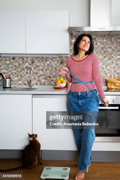 millennial woman and cat at the kitchen - gewicht verlieren stock-fotos und bilder