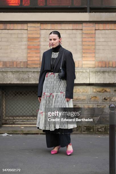 Guest wears red and silver earrings, a black wool turtleneck pullover, a red pearls necklace, a white lace print pattern long ruffled dress with red...