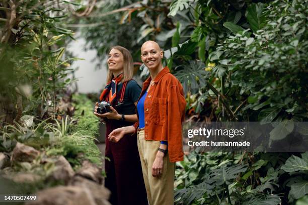 two young female tourists exploring botanical garden - alopecia stockfoto's en -beelden