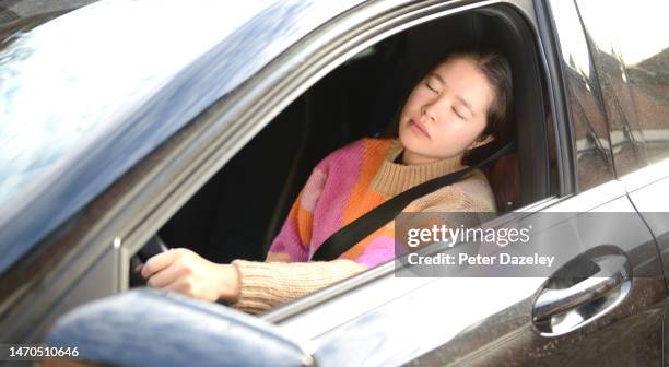 woman in left hand drive car falling asleep - woman filling out paperwork stock-fotos und bilder