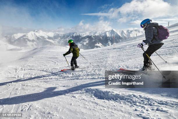 mother and son enjoy a skiing together in mountains on a sunny winter day - austria skiing stock pictures, royalty-free photos & images