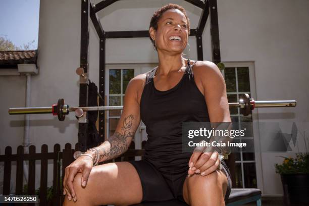 portrait happy, confident woman weightlifting in sunny backyard - basingstoke stock-fotos und bilder