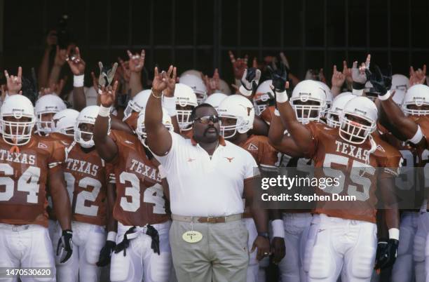 Jeff " Mad Dog " Madden, strength and conditioning coach for the University of Texas Longhorns stands with the team and gives the Texas horn sign...