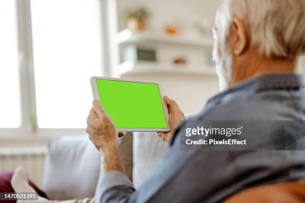 watching green mock-up screen on digital tablet - senior men computer stock pictures, royalty-free photos & images