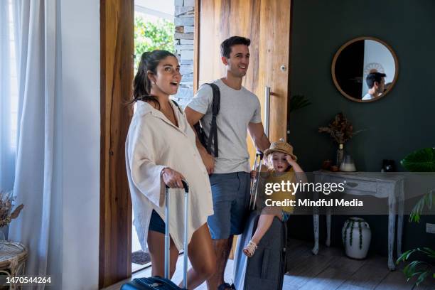junges lateinamerikanisches paar und ihre kleine tochter betreten ihr hotelzimmer mit ihren koffern und betrachten ehrfürchtig die räumlichkeiten - hotelzimmer tür stock-fotos und bilder